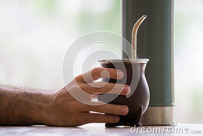 Selective focus shot of a hand holding a calabash mate cup with straw Stock Photo