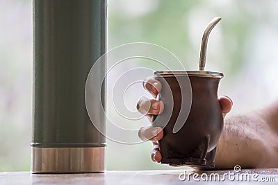 Selective focus shot of a hand holding a calabash mate cup with straw Stock Photo