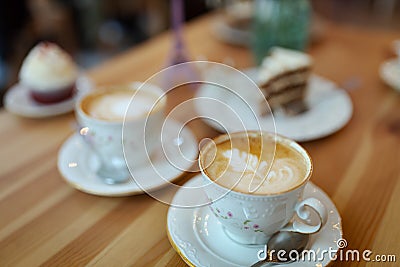 Selective focus shot of two cups of cappuccino coffee with foam on a wooden table Stock Photo