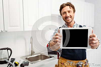 Focus of smiling plumber showing digital Stock Photo