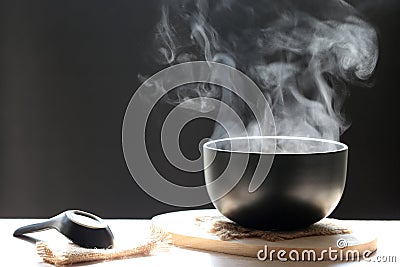 Selective focus of smoke rising with hot soup in cup and spoon o Stock Photo