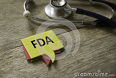 Selective focus of stethoscope and a stack of colorful speech bubbles written with FDA on wooden background Stock Photo