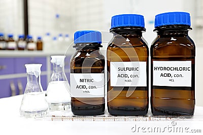 Selective focus of strong Nitric, Sulfuric and Hydrochloric acids in brown amber bottle. Stock Photo