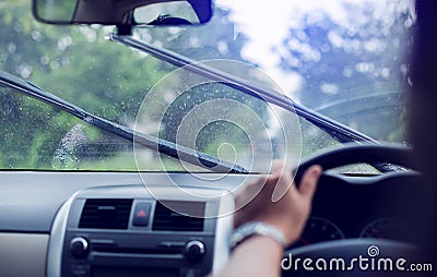 Selective focus to man driving a car with rain droplet on windshield and wiper. Windshield wipers from inside of car Stock Photo