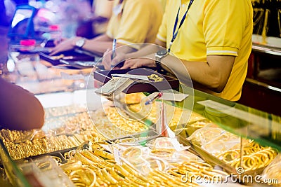 Selective focus to staff are counting banknote, customers are buying gold jewelry in the gold shop Stock Photo