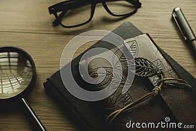 Selective focus of vintage notebook, magnifying glass,pen and glasses on wooden background Stock Photo