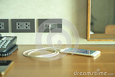 Selective focus on wall electrical outlet with charger of mobile phone Stock Photo