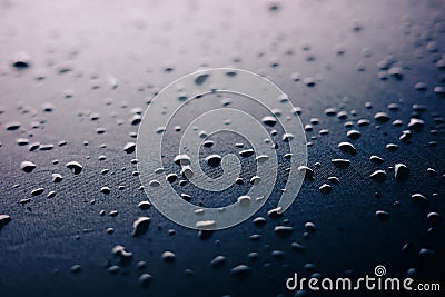 Selective focus on water drops on slippy surface of black synthetic fabric with bright light from background Stock Photo