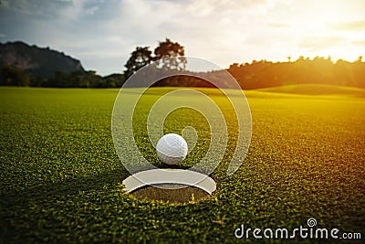 Selective focus. white golf ball near hole on green grass good f Stock Photo