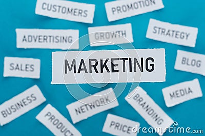 Selective focus of word marketing and components of marketing on pieces of paper on blue . Stock Photo