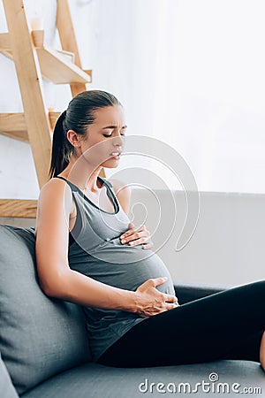 Selective focus of pregnant sportswoman suffering Stock Photo