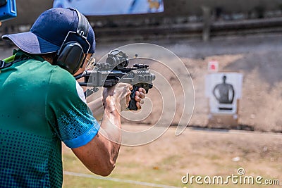 Selective focus of man holding and fire sub machine gun to target in gun shooting competition Editorial Stock Photo
