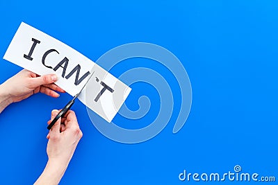 Self confidence concept. Cutting the letter t of written word I can`t by sciccors. Blue background top view copy space Stock Photo
