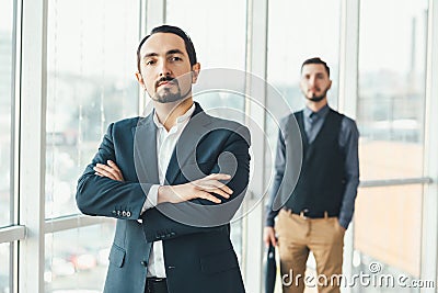 Self-confident businessman on the forefront, looking at the camera, his hands folded, while his defeated competitor Stock Photo
