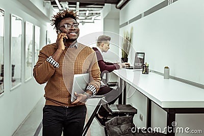 Self-conscious African American guy talking on mobile phone Stock Photo