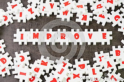 Self improvement or positive motivation concept, white puzzle jigsaw with alphabet building the word Improve at the center of dark Stock Photo