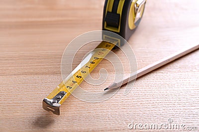 Self retracting metal measuring tape and pencil on wooden table, closeup Stock Photo