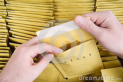 Self sealed mailing envelope quality inspection. Male hands open one yellow bubble mailer out of a bunch of shipping airmails Stock Photo