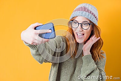Selfie. Close up girl takes photo of himself with her smartphone, isolated on yellow background Stock Photo