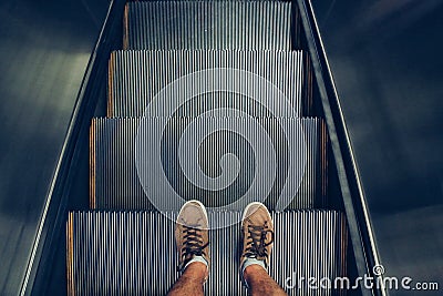 Selfie of feet in sneaker shoes on escalator steps in vintage style Stock Photo