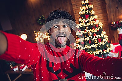 Selfie of funny joking arabian man making new video fooling christmas vacation party stick out tongue at decorative home Stock Photo