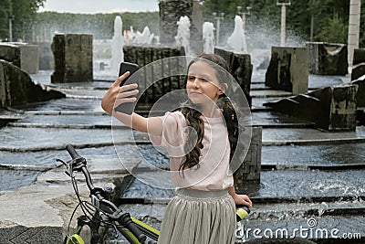 Selfie of a girl near a Bicycle and a fountain. Long hair. Outdoor activity. Stock Photo