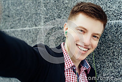 Selfie photo of attractive smiling young man in plaid shirt. Stock Photo
