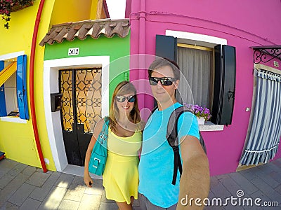 SELFIE: Smiling tourists pose in front of colorful buildings in sunny Venice. Stock Photo