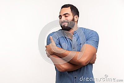 Selfish narcissistic man with beard hugging itself, comforting and supporting, fulfilling his needs to feel happiness, self esteem Stock Photo