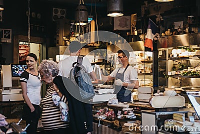 Seller and customers inside charcuterie and cheese stand in Borough Market, London, UK. Editorial Stock Photo