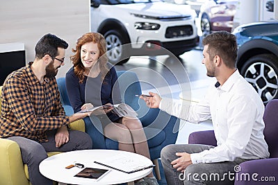 Seller offering exclusive car to marriage watching brochure in the showroom Stock Photo