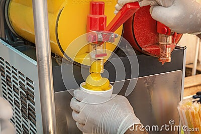 Seller pours frozen juice or serbet into a once-only glass from the machine. Stock Photo