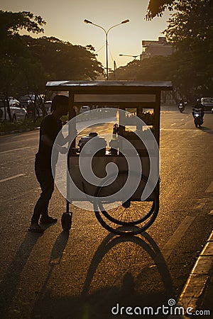 The seller walks to move his food-cart offside the street Editorial Stock Photo