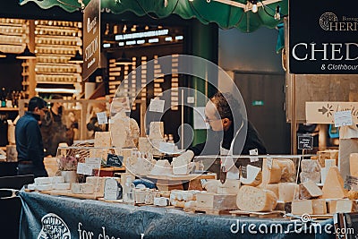 Seller working at a cheese stand in Borough Market, London, UK Editorial Stock Photo