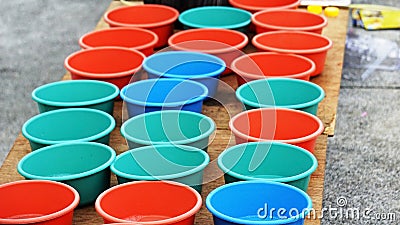 Selling Colorful tubs lined together on a wooden platform. Small plastic tubs filled with soap solution for blowing bubbles Stock Photo