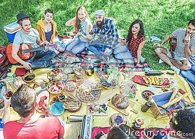Semi flat view of friends making picnic in nature park sitting on grass- Young people having fun playing music, eating and Stock Photo