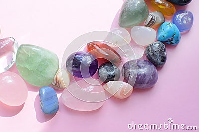 Semi-precious beautiful stones of bright colors lie on a pink background. Amethyst, rose quartz, agate, apatite, aventurine, Stock Photo