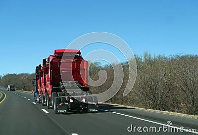 Semi tractor hauling three semi trucks, red, on highway Editorial Stock Photo