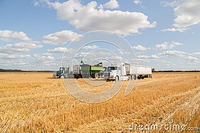 Semi truck and farm machinery parked in a field at harvest Stock Photo