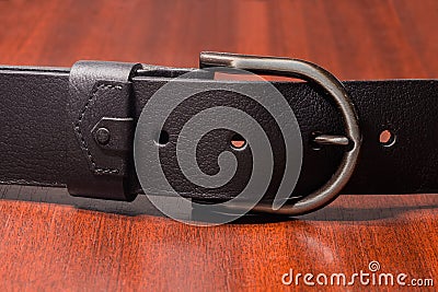 Semicircular frame buckle of black leather belt on wooden table Stock Photo