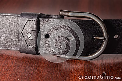 Semicircular frame buckle of black leather belt on wooden table Stock Photo