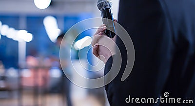 Seminar presenter`s hand holding microphone at conference giving speech. Speaker giving lecture to business audience. Stock Photo