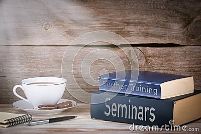 Seminars and Further Training. Stack of books on wooden desk Stock Photo