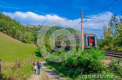 SEMMERING, AUSTRIA, OCTOBER 3, 2015: a train is passing a family having a hiking trip on semmeringbahntrail in austria Editorial Stock Photo