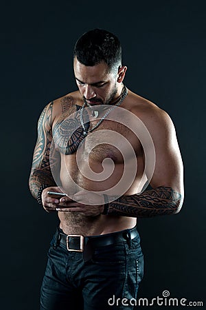 Send message. Handsome fit man send message smartphone. Muscular tattooed athlete look attractive. Messaging Stock Photo