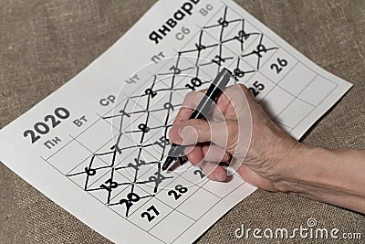 Senile female hand crosses out the number on the calendar with a marker Stock Photo