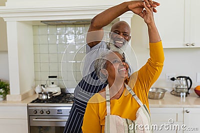 Senior african american couple dancing together in kitchen smiling Stock Photo