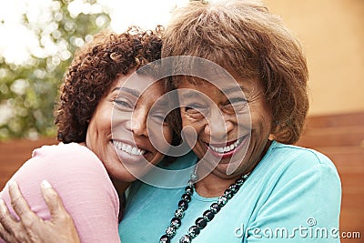 Senior African American mum and her middle aged daughter smile to camera embracing, close up Stock Photo