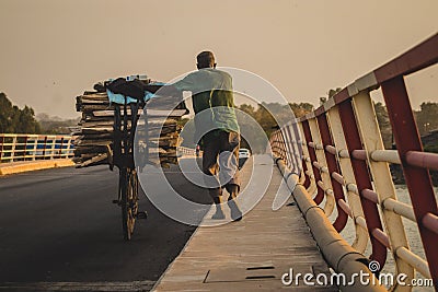 African pushing a bike over a bridge Editorial Stock Photo