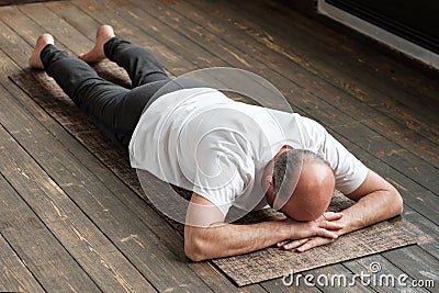 Senior aged man resting after yoga exercise on floor. Sports at home for health. Stock Photo
